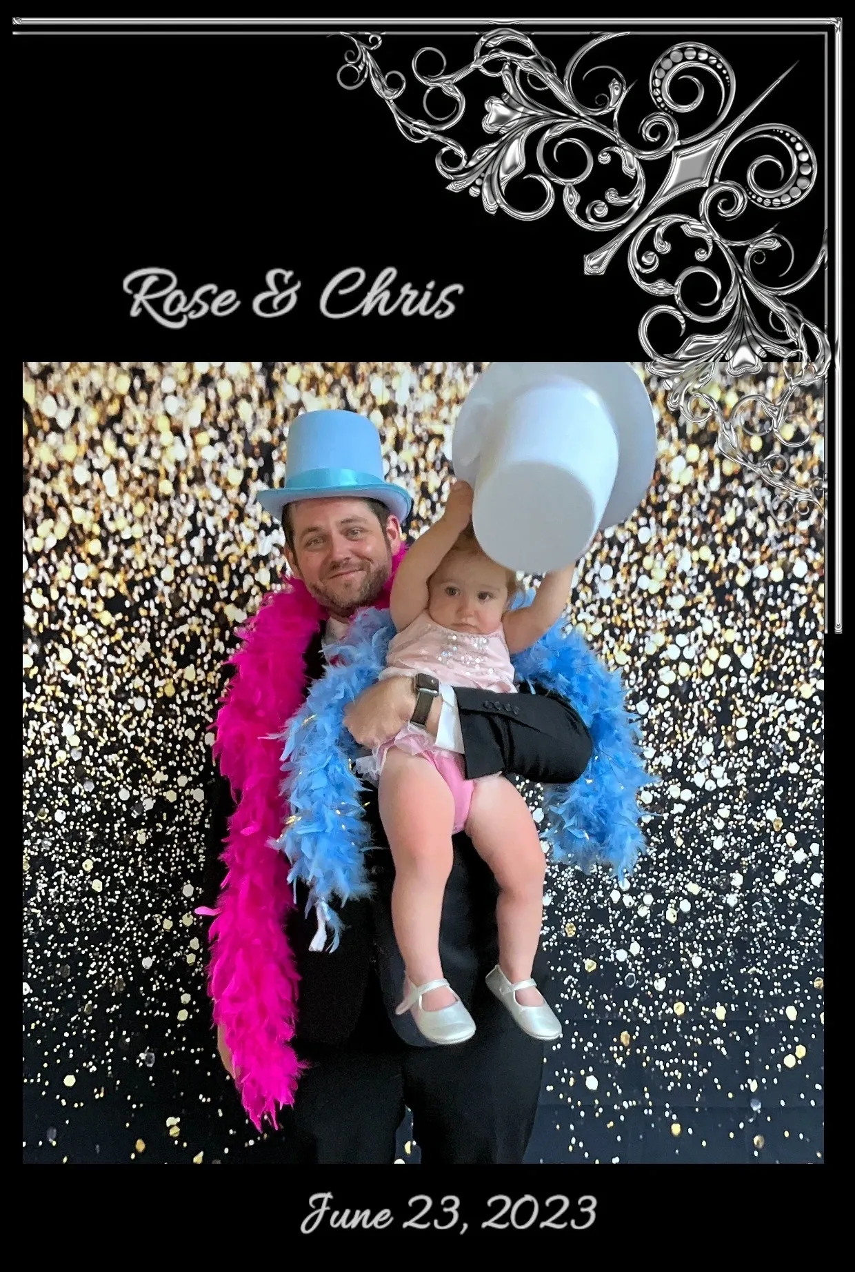 A man holding a baby in front of a silver background.