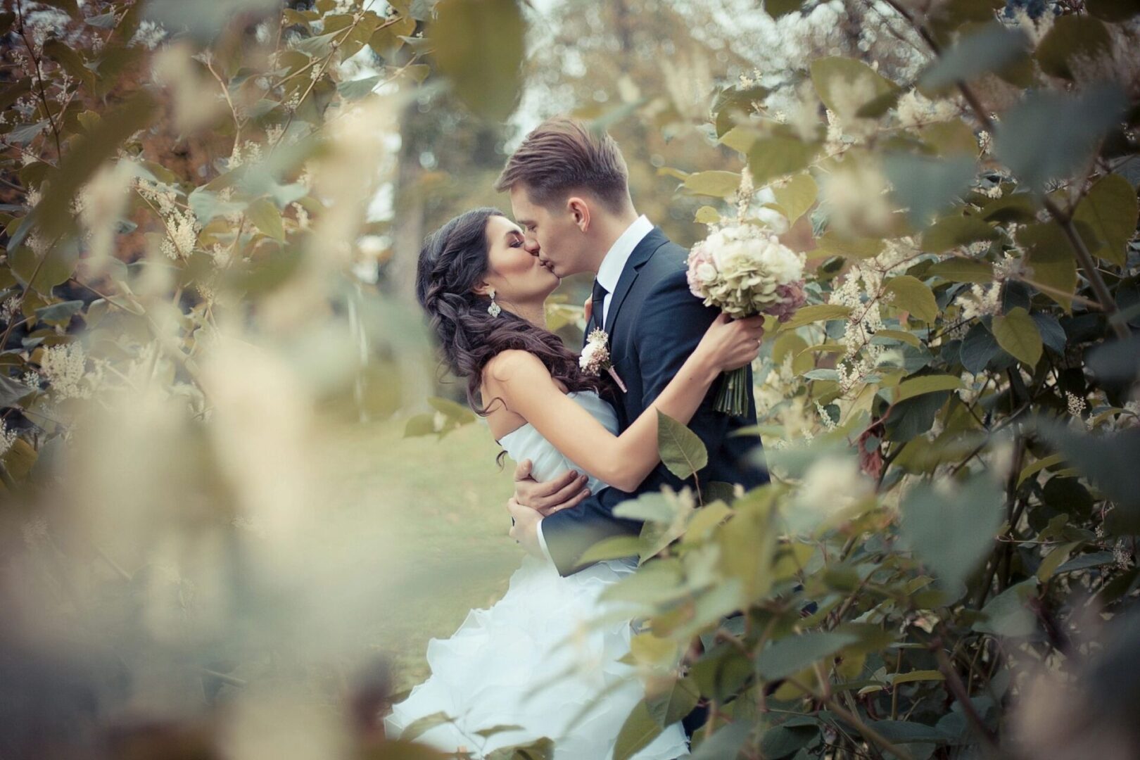 A man and woman kissing in the trees.