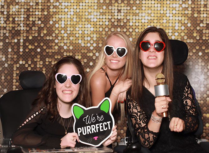 A group of girls posing for a photo in front of a sequined wall.